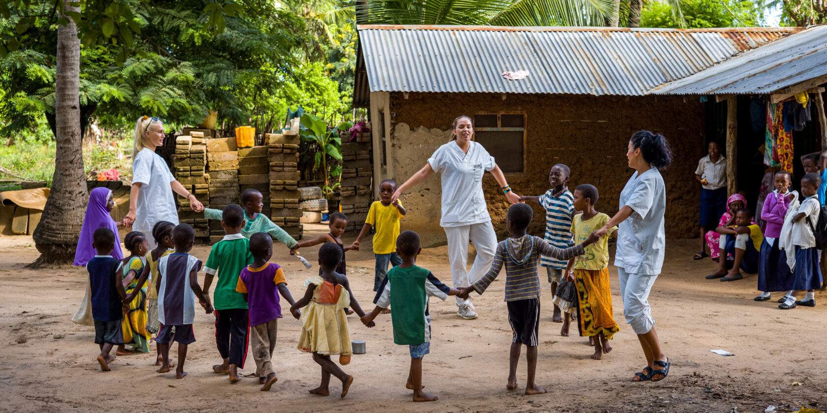 Students and children forming a circle by holding hands, spinning around and singing