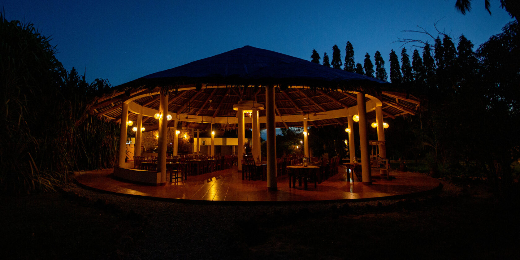 The makuti roof with the dining place beneath alit in the night
