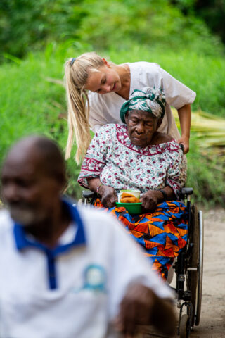 Student assisting an elderly woman in a wheel chair