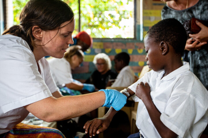 Student applying a bandaid to a wound on a childs arm